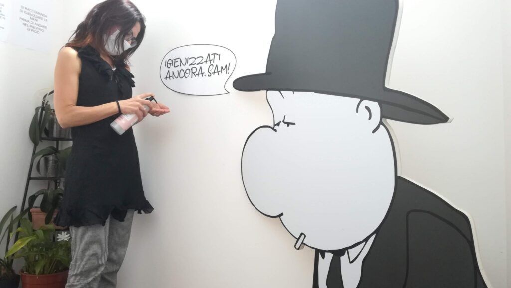 in tempo di pandemia, il cartonato di Big Sleeping fuori dalla bottega ammonisce a igienizzarsi